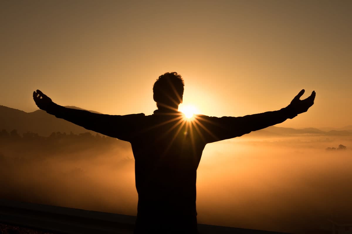 Someone on a mountain basks in the sunrise