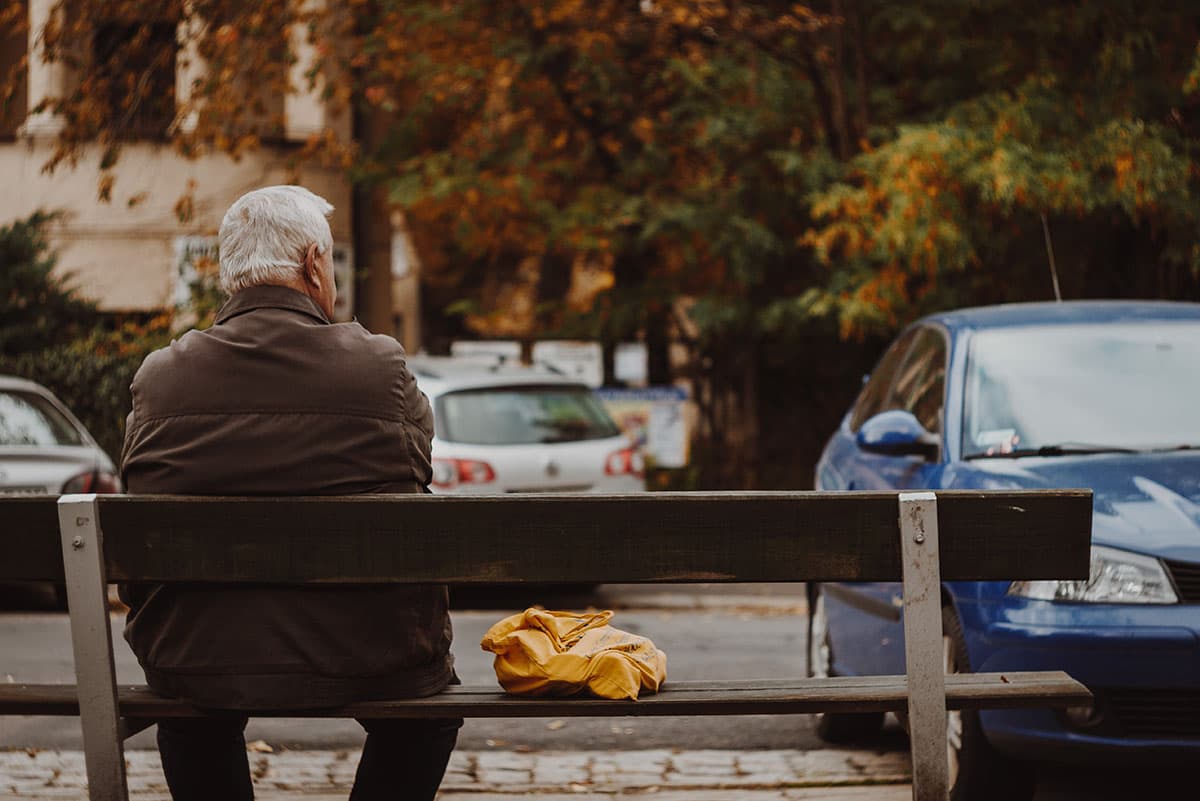 A man sits and reflects on a city bench