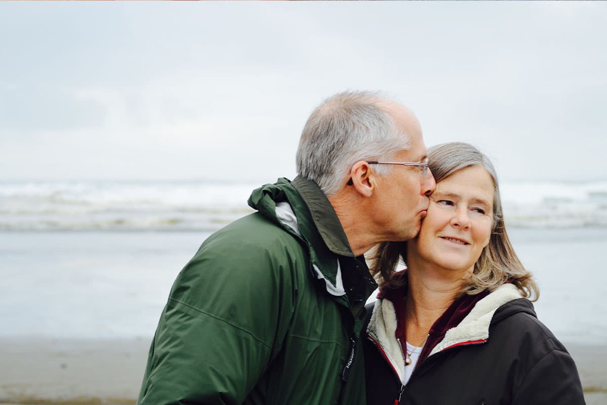 A husband kisses his wife on the cheek