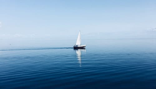 A small sail boat glides along the water