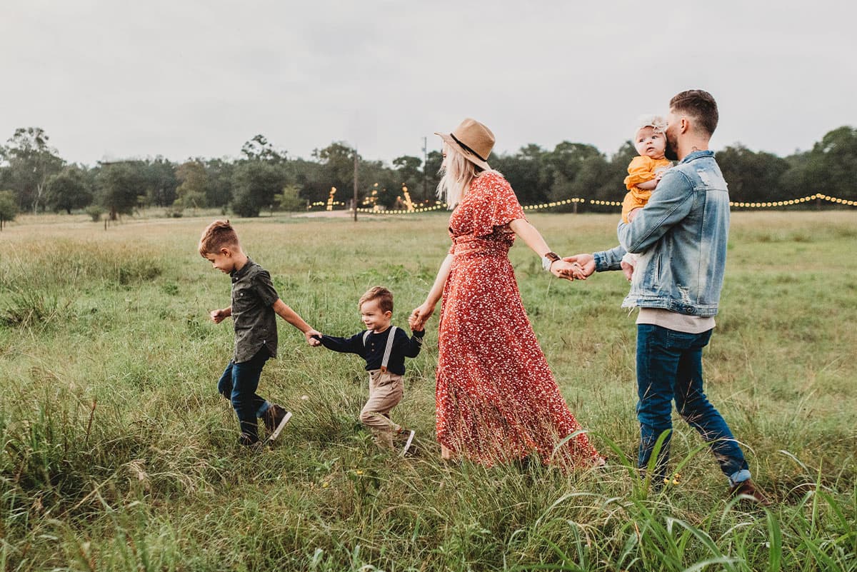 Family walking hand in hand through a grassy field outdoors