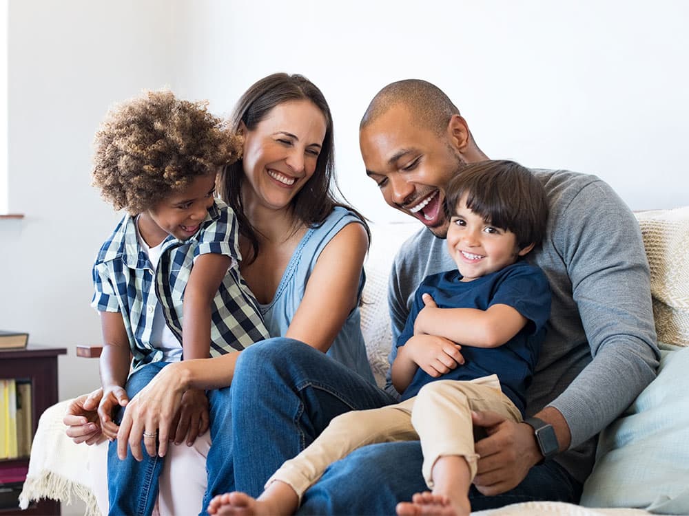 Smiling family sitting together on a couch at home