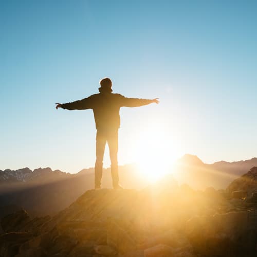 Someone feeling free on a mountain at sunset