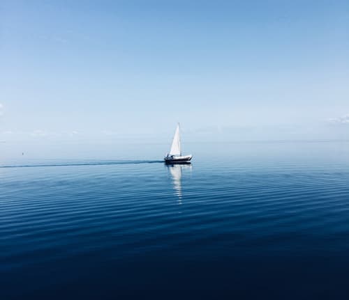 Small sailboat on calm blue water under a clear sky
