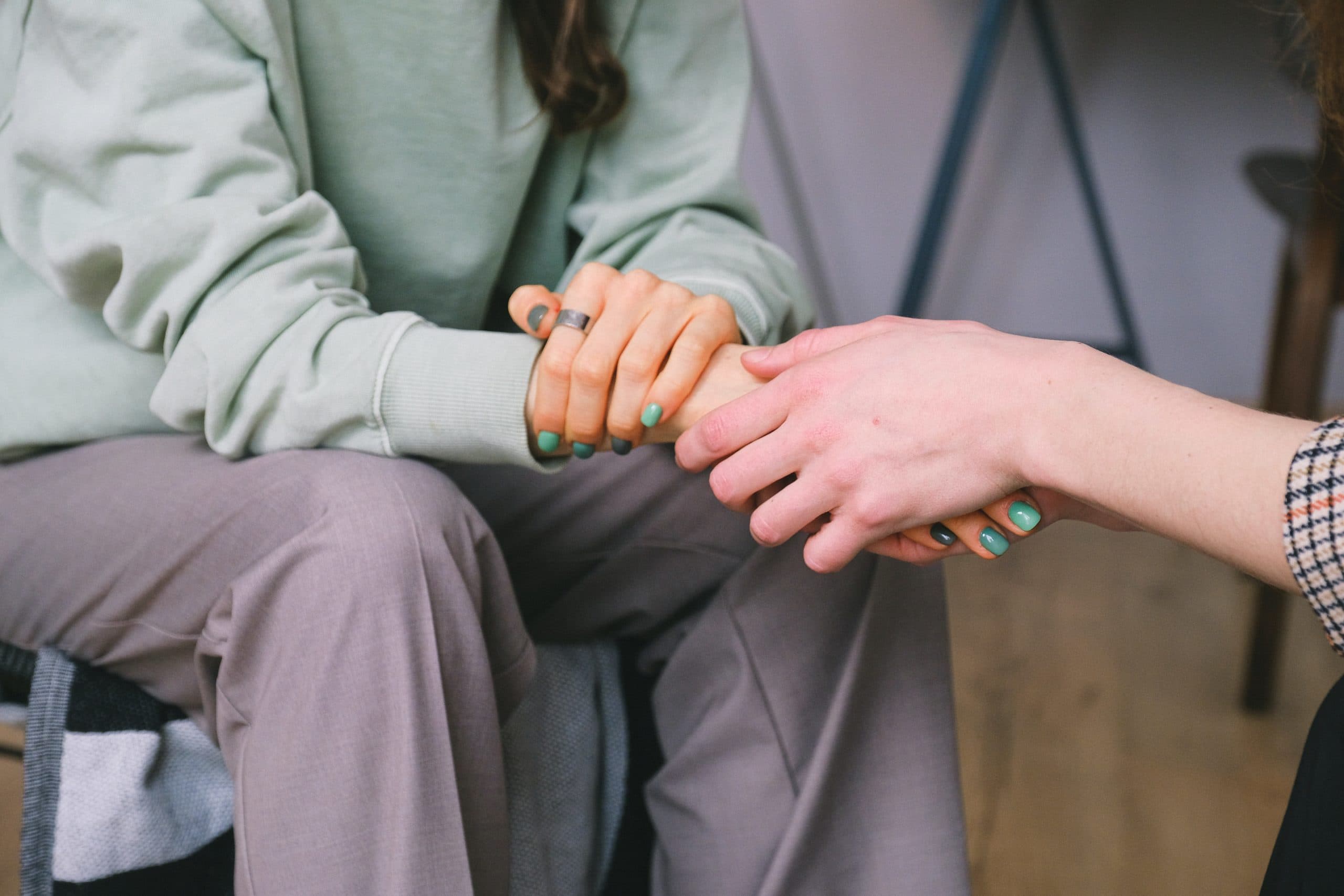 close up on two people holding hands comfortingly