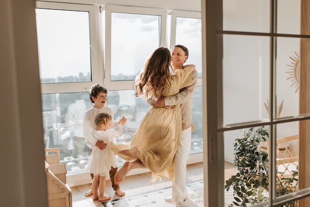 Parents dancing and playing around while their kids are watching them and smiling