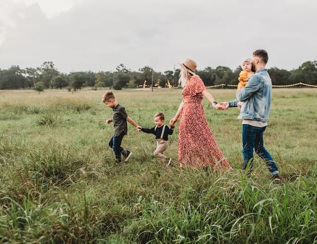 Parents and their three kids running through a green field