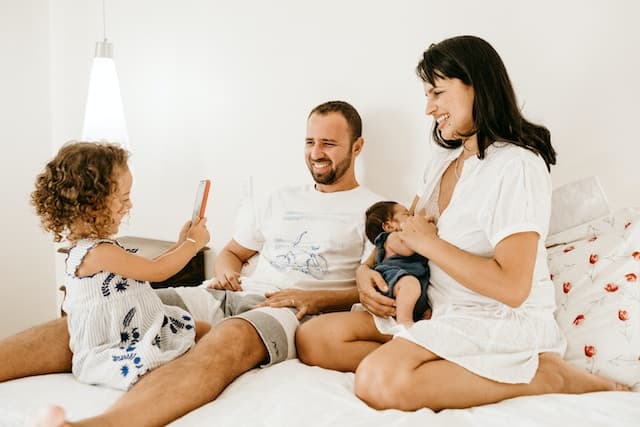 family sitting on bed laughing together