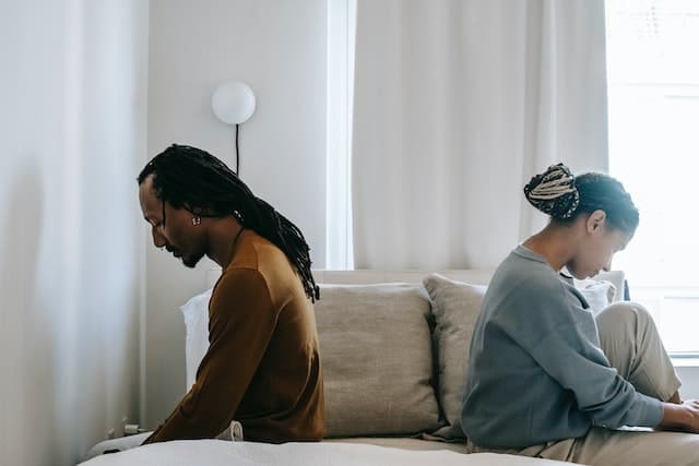 Couple sitting on the opposite sides of the bed to symbolize reasons you might need marriage counseling.
