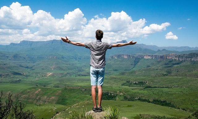 Guy at the top of hike holding his arms out
