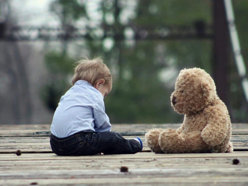 little boy sitting alone with teddy bear