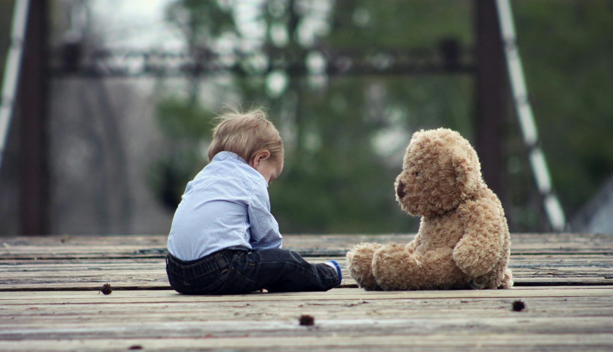 little boy sitting alone with teddy bear