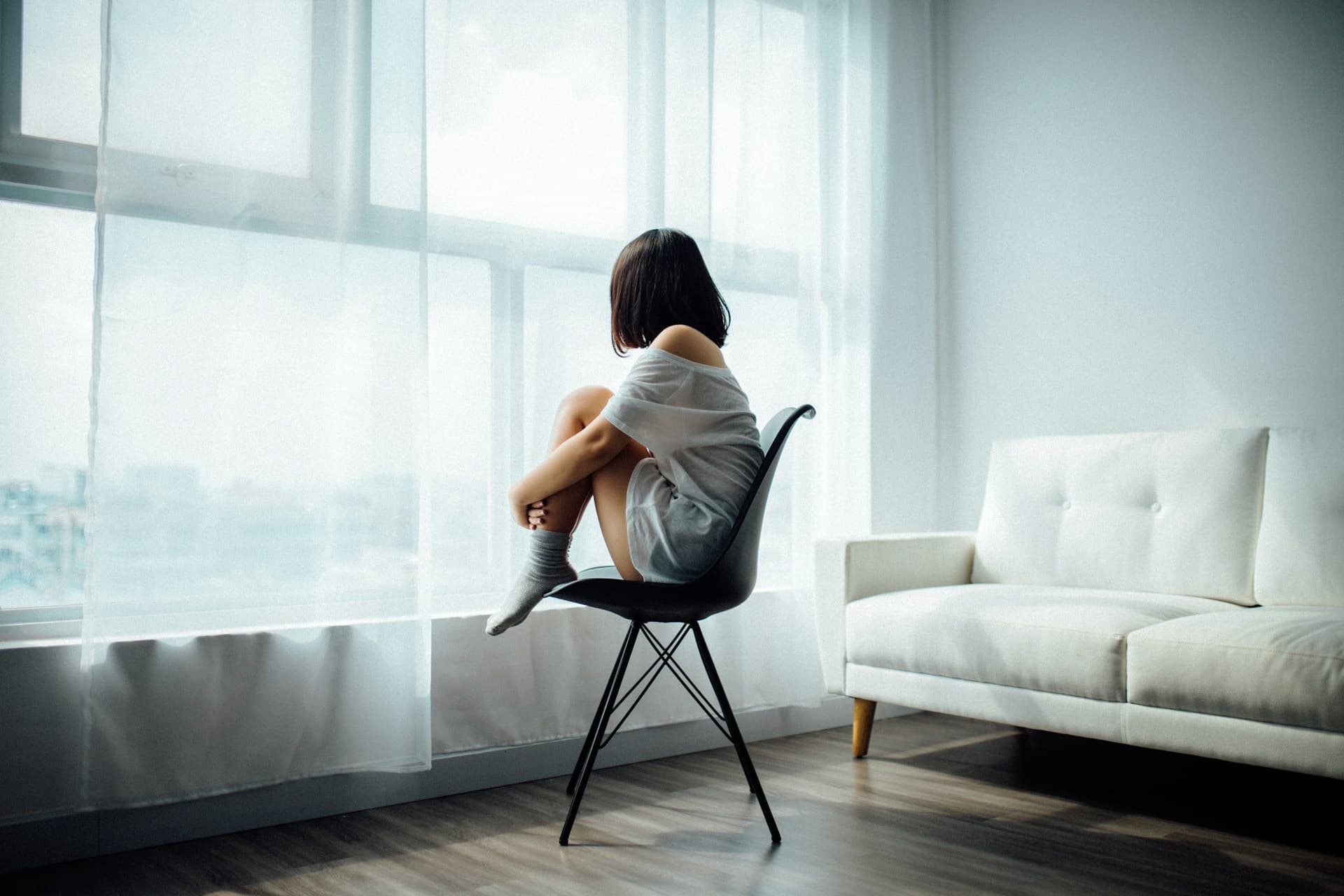A person sitting in a chair with their legs on the seat.