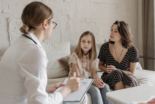 A girl and her mother sitting in front of a doctor