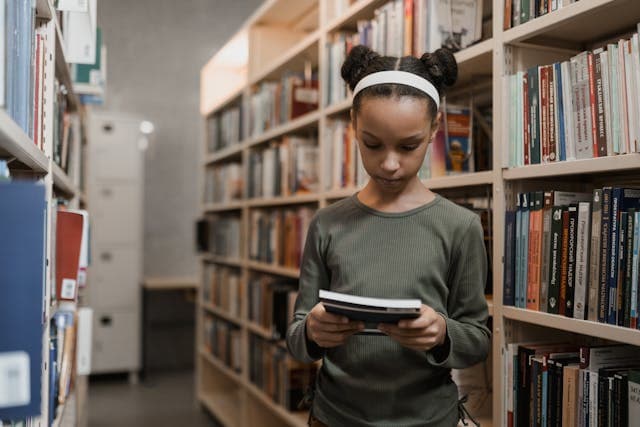 A young girl reading a book in a library
