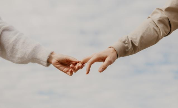 Two people holding hands against a white, foggy background.